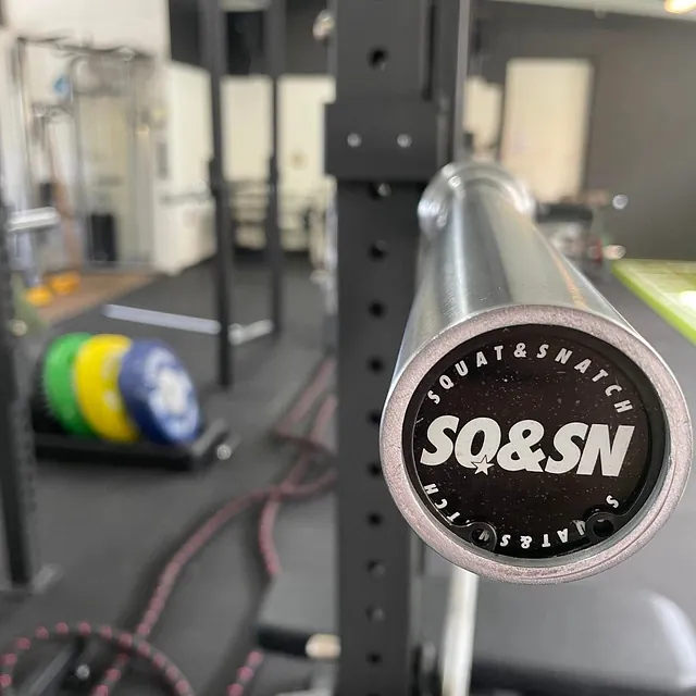 Nærbilde av vektstang med teksten SQ&SN Squat & Snatch på endestykket